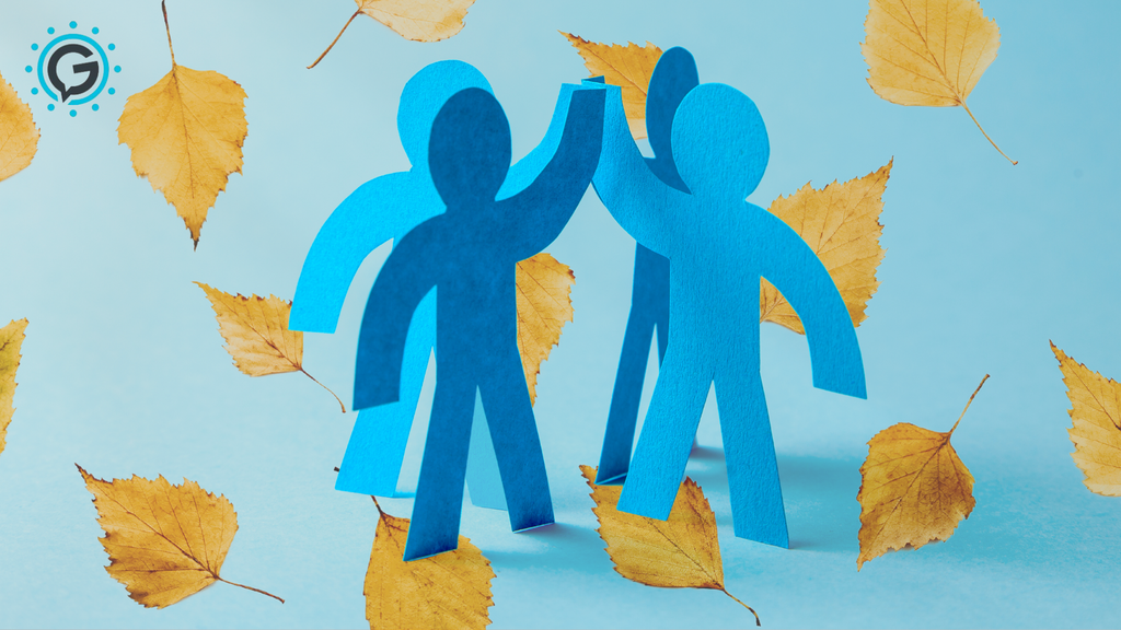 Four blue paper cutouts positioned so that they are in a circle high-fiving with yellow leaves falling behind it.