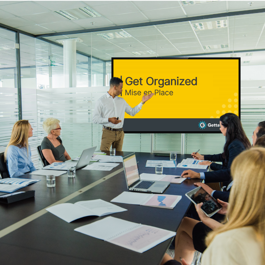 A man introducing the meeting module video on a screen in a conference room of employees.
