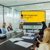 A man introducing the meeting module video on a screen in a conference room of employees.