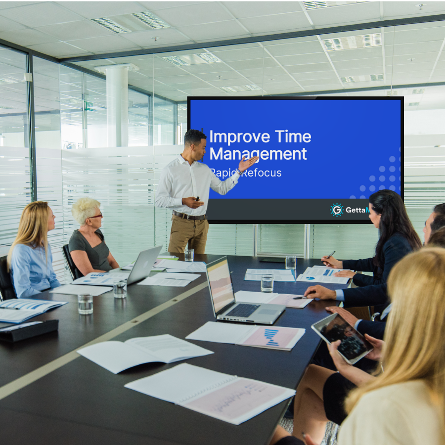 A man introducing the meeting module video on a screen in a conference room of employees.