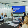 A man introducing the meeting module video on a screen in a conference room of employees.
