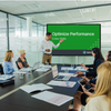 A man introducing the meeting module video on a screen in a conference room of employees.