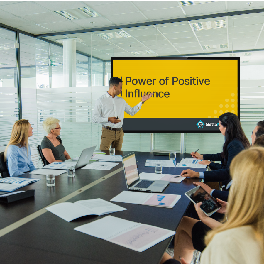 A man introducing the meeting module video on a screen in a conference room of employees.