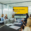 A man introducing the meeting module video on a screen in a conference room of employees.